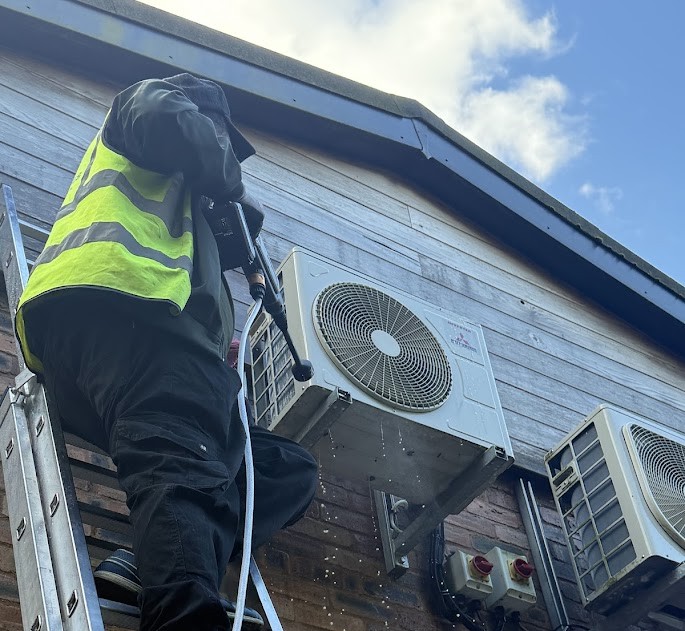 Engineer servicing outdoor air conditioning unit during annual maintenance